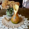 A vase made from a dried gourd. It is a brown to green ombre stain, with a iridescent butterfly wood burned on the front.  